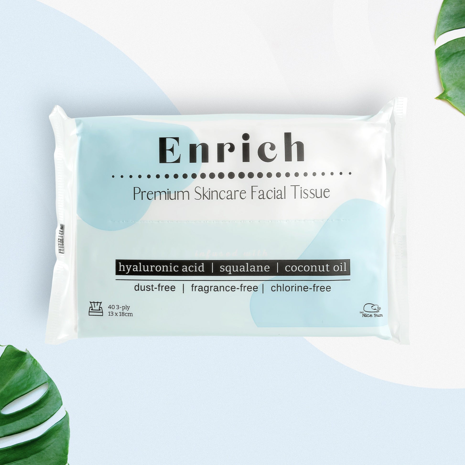 A pack of Enrich premium skincare facial tissues, with packaging that highlights features such as hylauronic acid, squalene, and coconut oil. The pack is white with blue and green design elements, and there are coconut oil plants in the background.